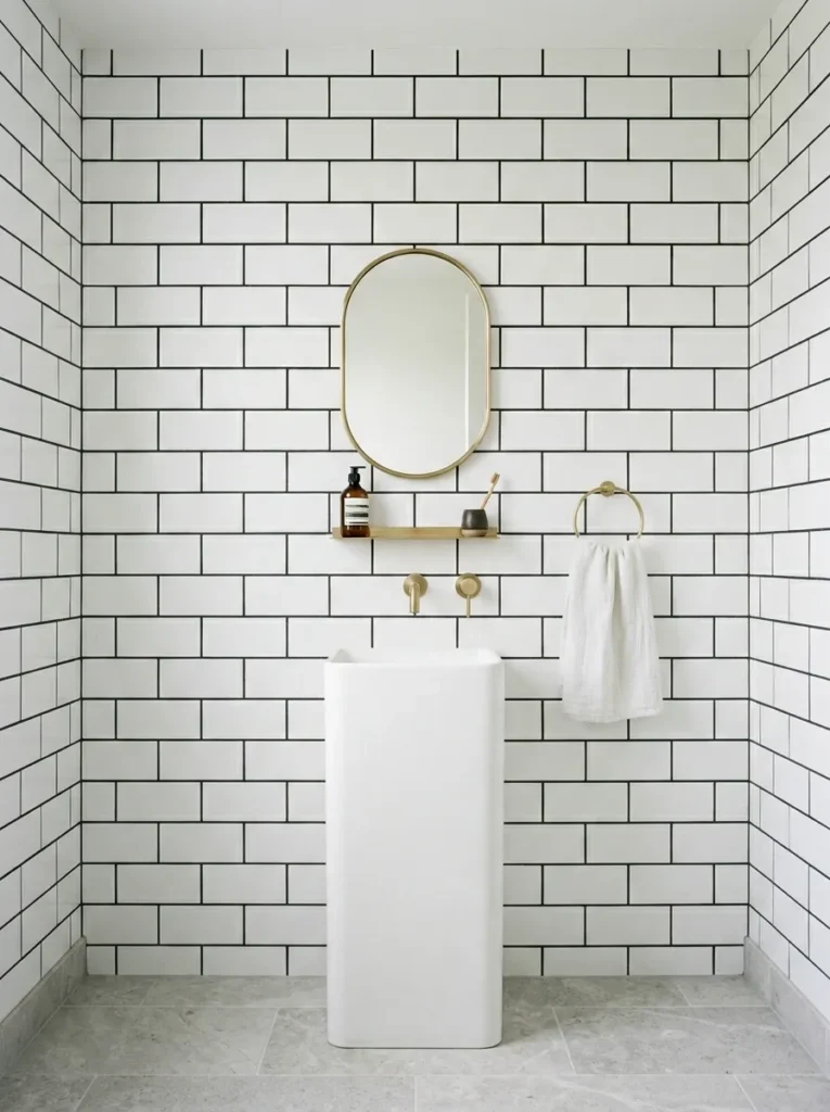 Small bathroom with crisp white subway tiles and dark charcoal grout lines creating a graphic grid pattern on the walls above a white freestanding basin