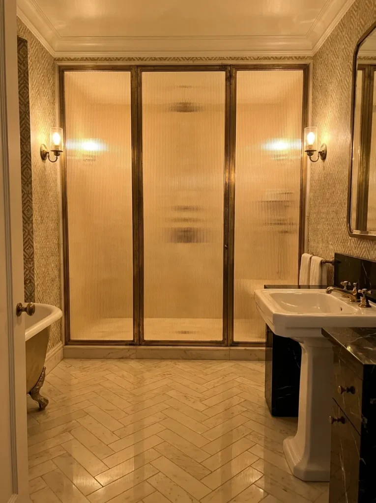 Elegant bathroom featuring fluted glass shower enclosure and brass detailing