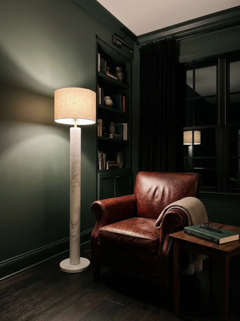  A tall marble-base floor lamp towering over a reading chair in a dark sophisticated living room